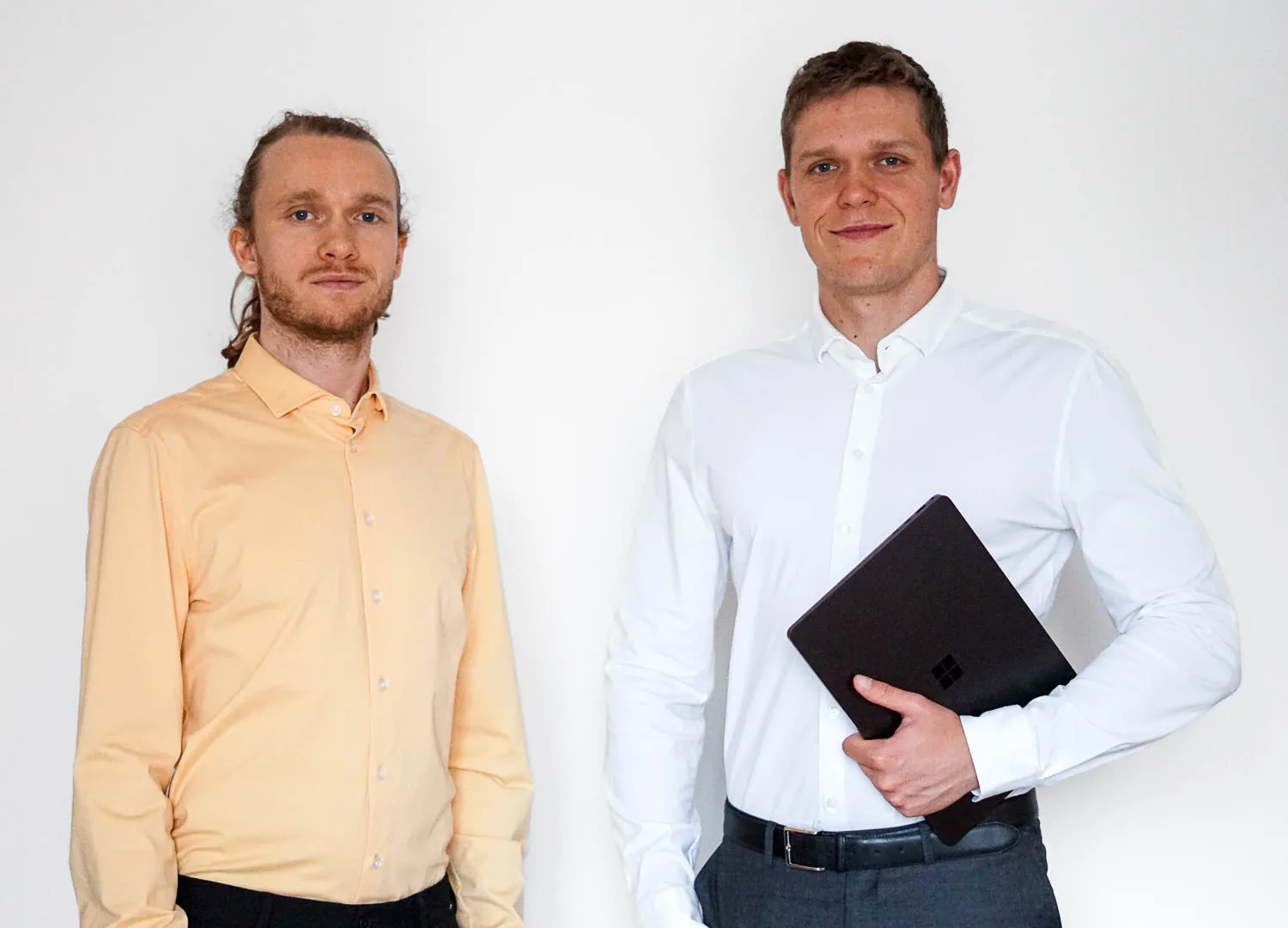 Adam Hjelmar og Mads-Bjørn Hjelmar står foran en lys væg