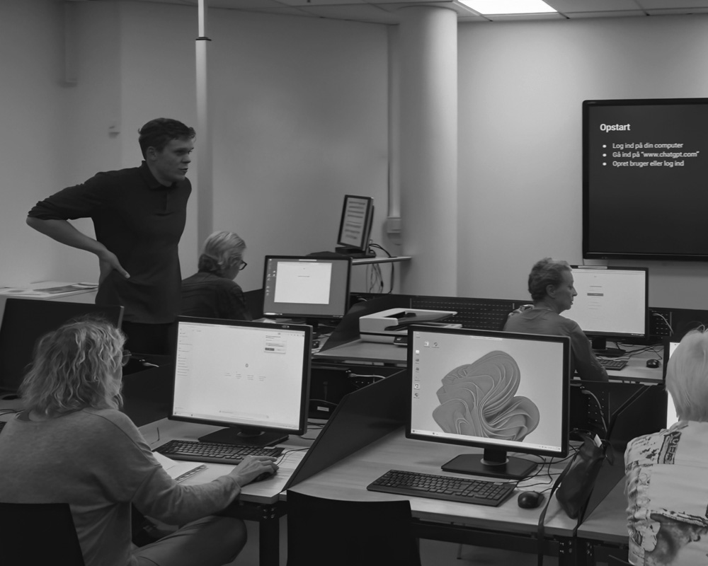 En af Momentum AI's stiftere underviser deltagere ved en ChatGPT-workshop med computere og præsentation